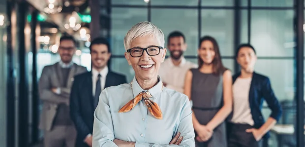 Symbolbild Führungskraft: Eine Frau steht im Büro vor ihrem Team