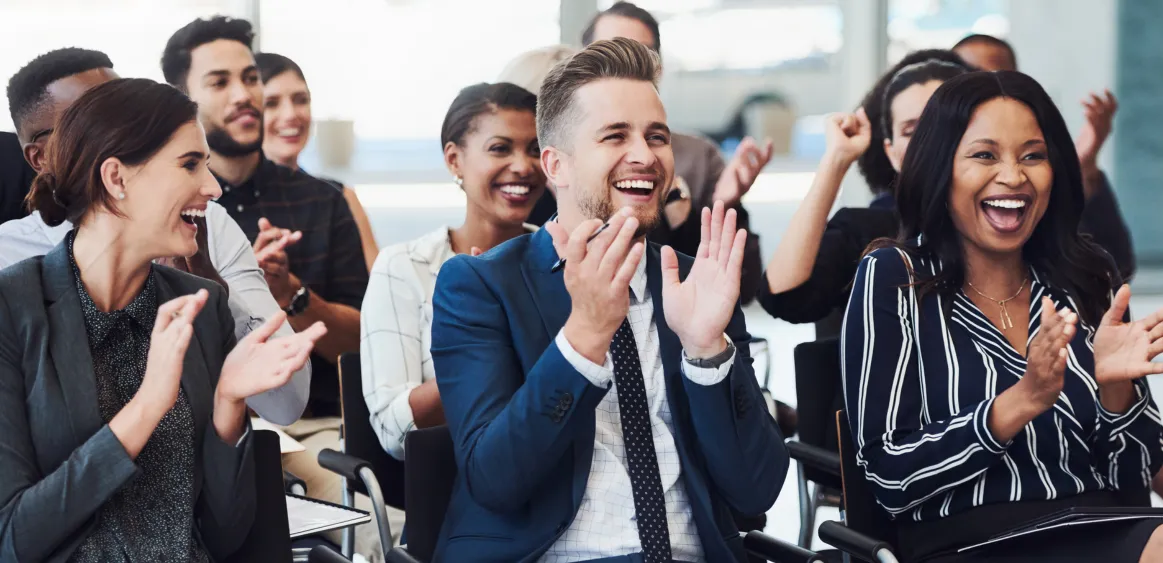 Symbolbild zufriedene Mitarbeiter: Menschen in Businesskleidung applaudieren